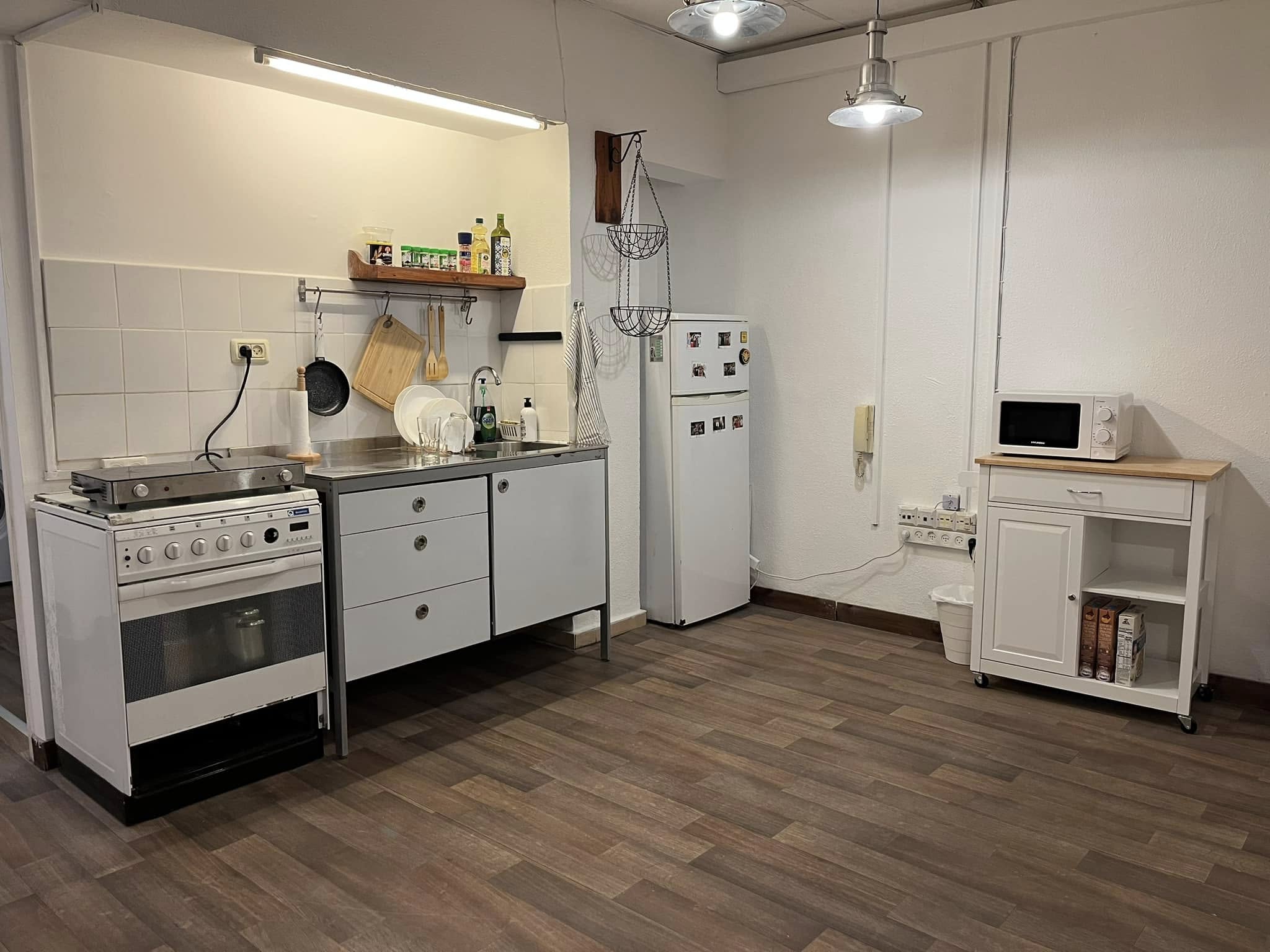 Kitchen with a freestanding gas range, sink, refrigerator and a movable prep cart